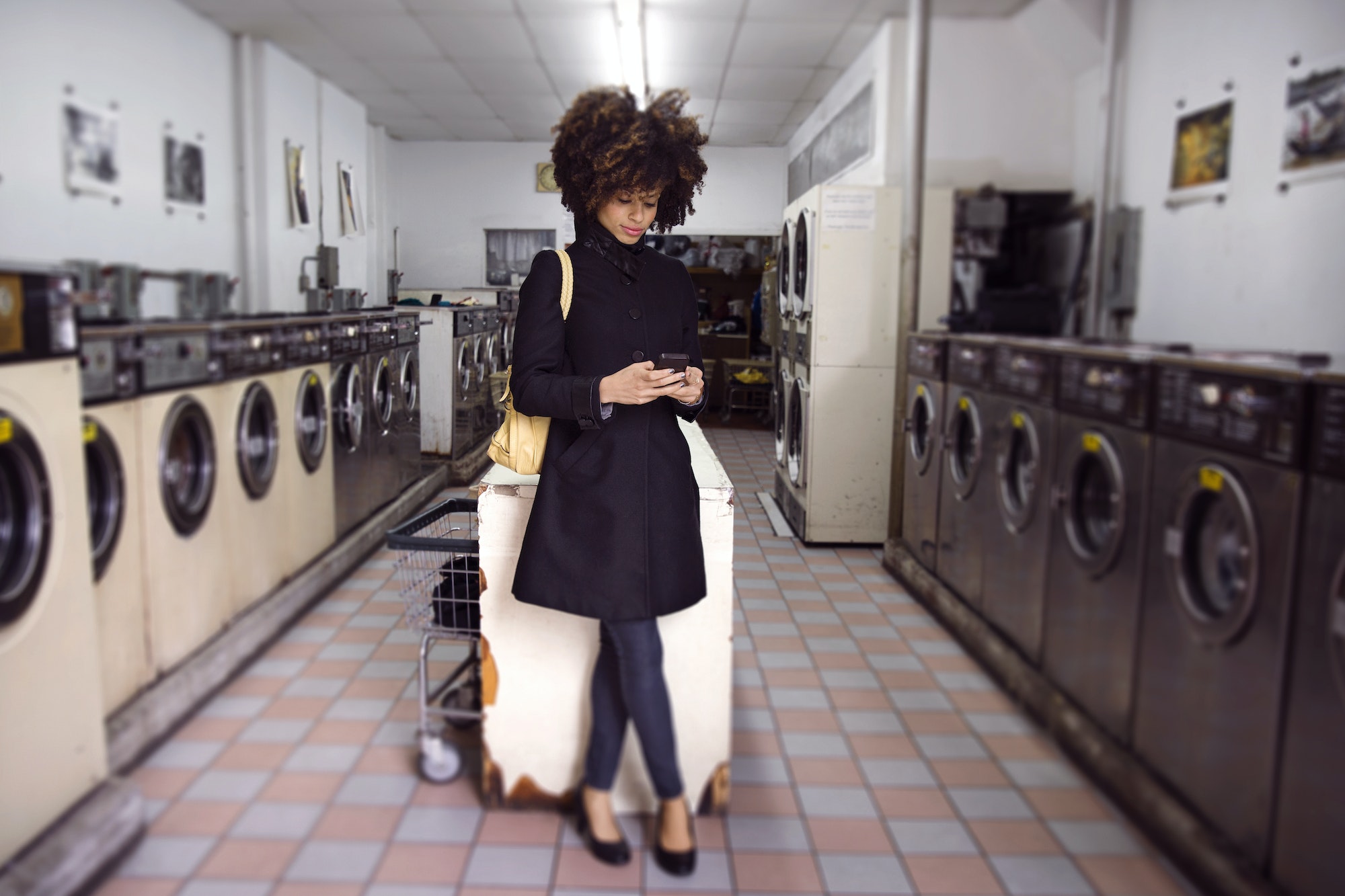 Full Length Of Woman Using Phone While Standing In Laundromat