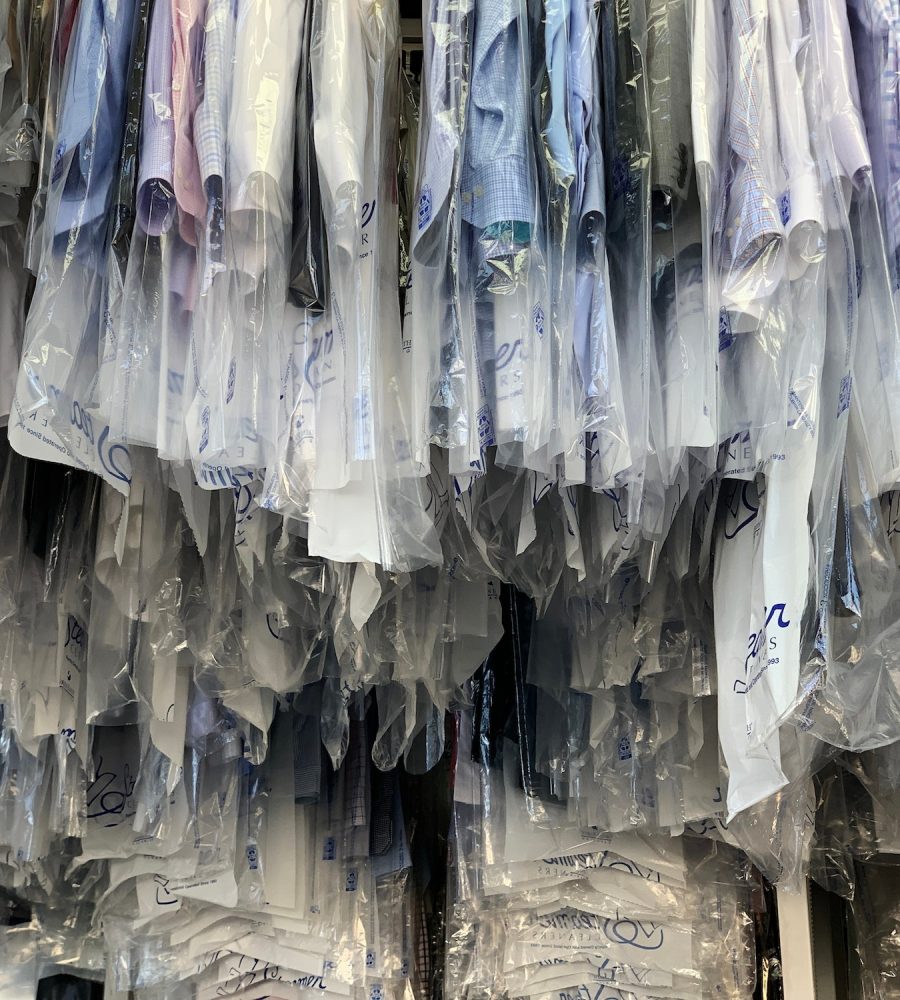 Racks of dry cleaning hanging on the conveyor belt at the dry cleaner. clothes in cleaning plastic.